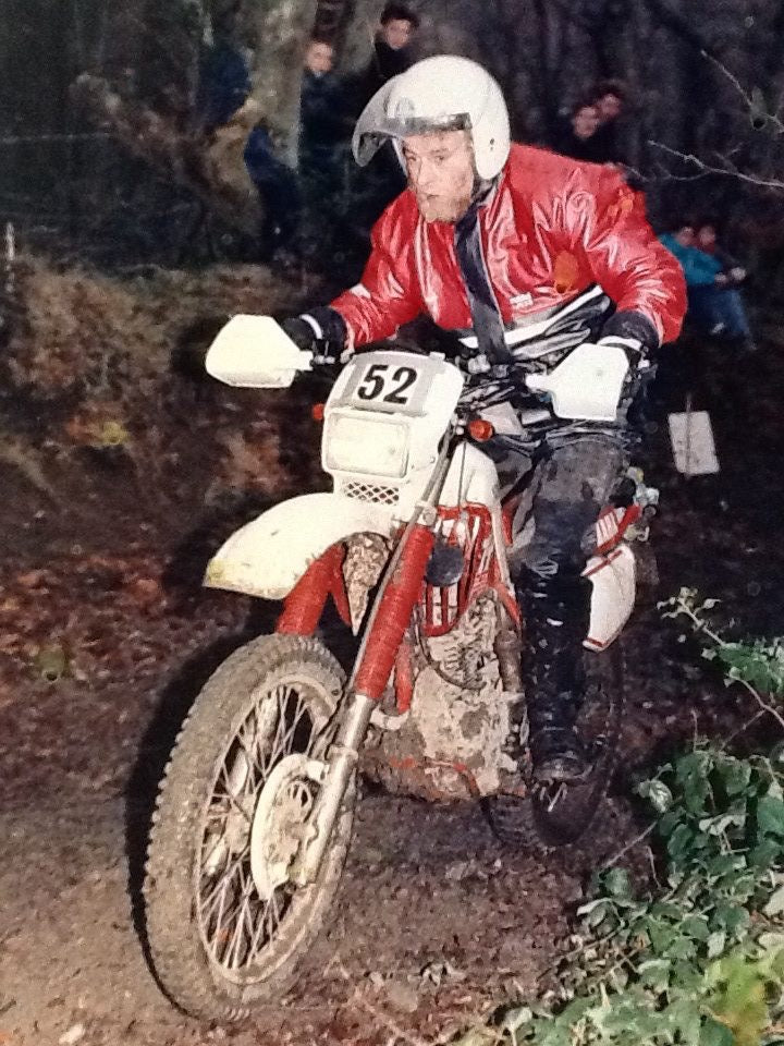 Rider number 52 in a red jacket competing on a classic enduro motorcycle
